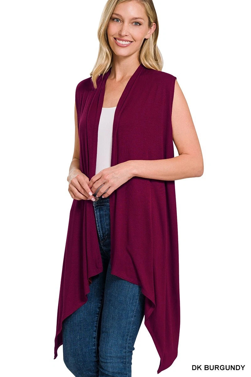 Woman wearing a burgundy sleeveless top with a white shirt and blue jeans on a white background