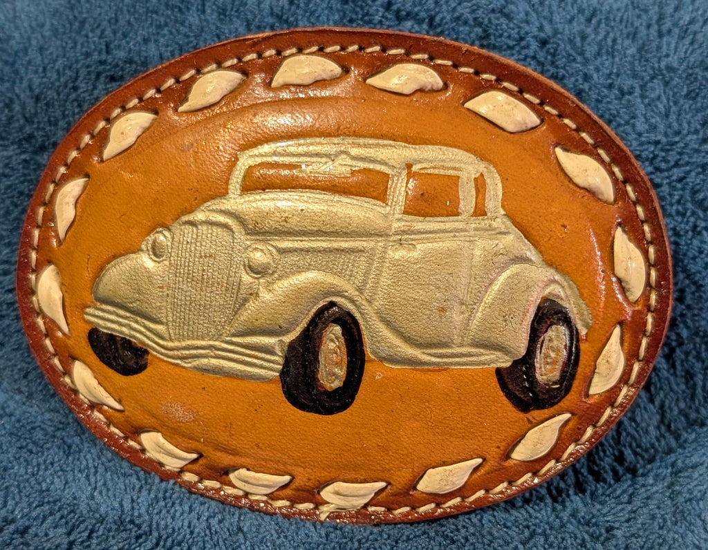 Leather belt buckle with vintage car design on a blue textured background