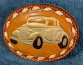 Leather belt buckle with vintage car design on a blue textured background