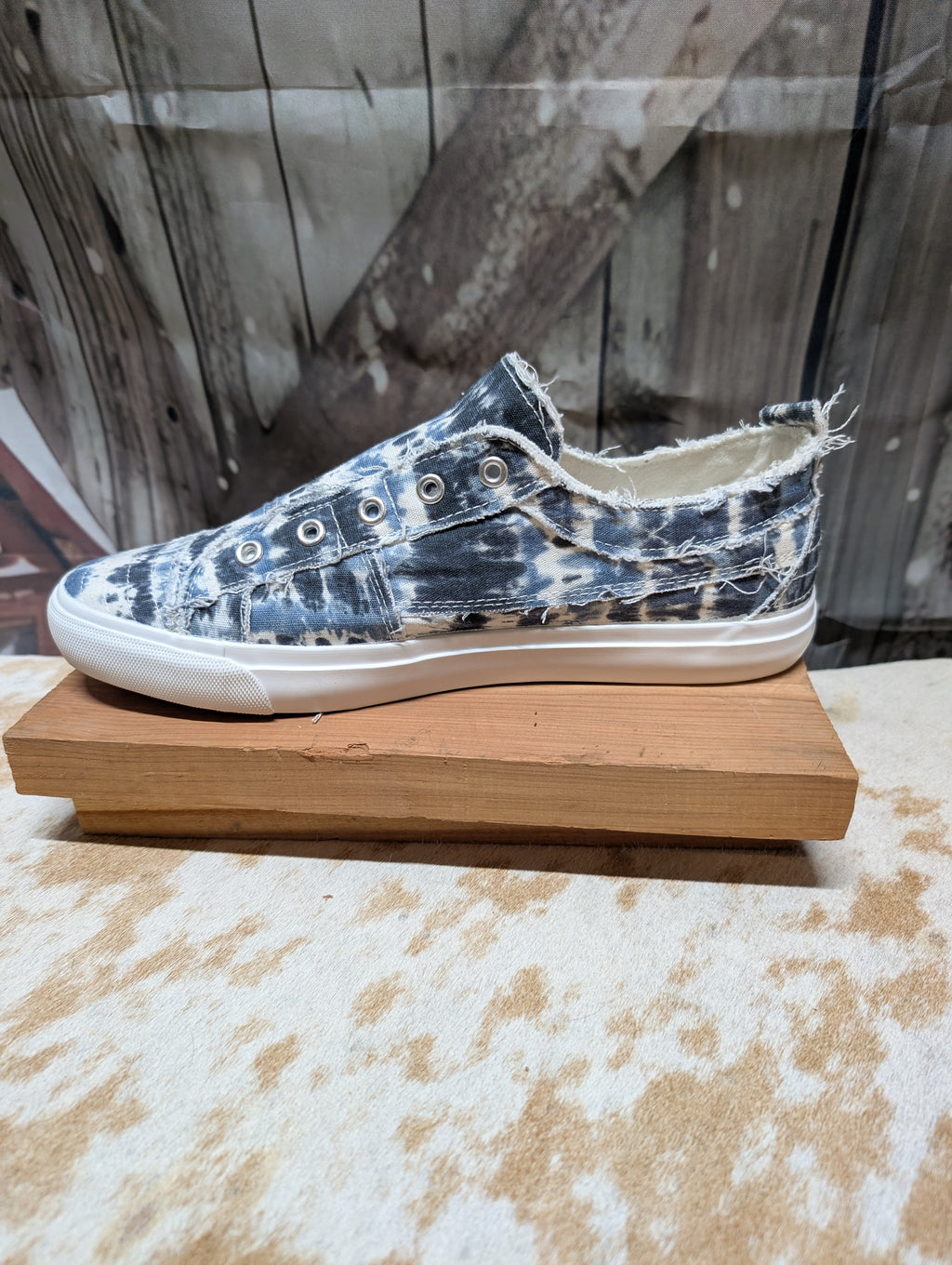 Blue and Whiter Sneaker with tie-dye pattern on a wooden block against a rustic background