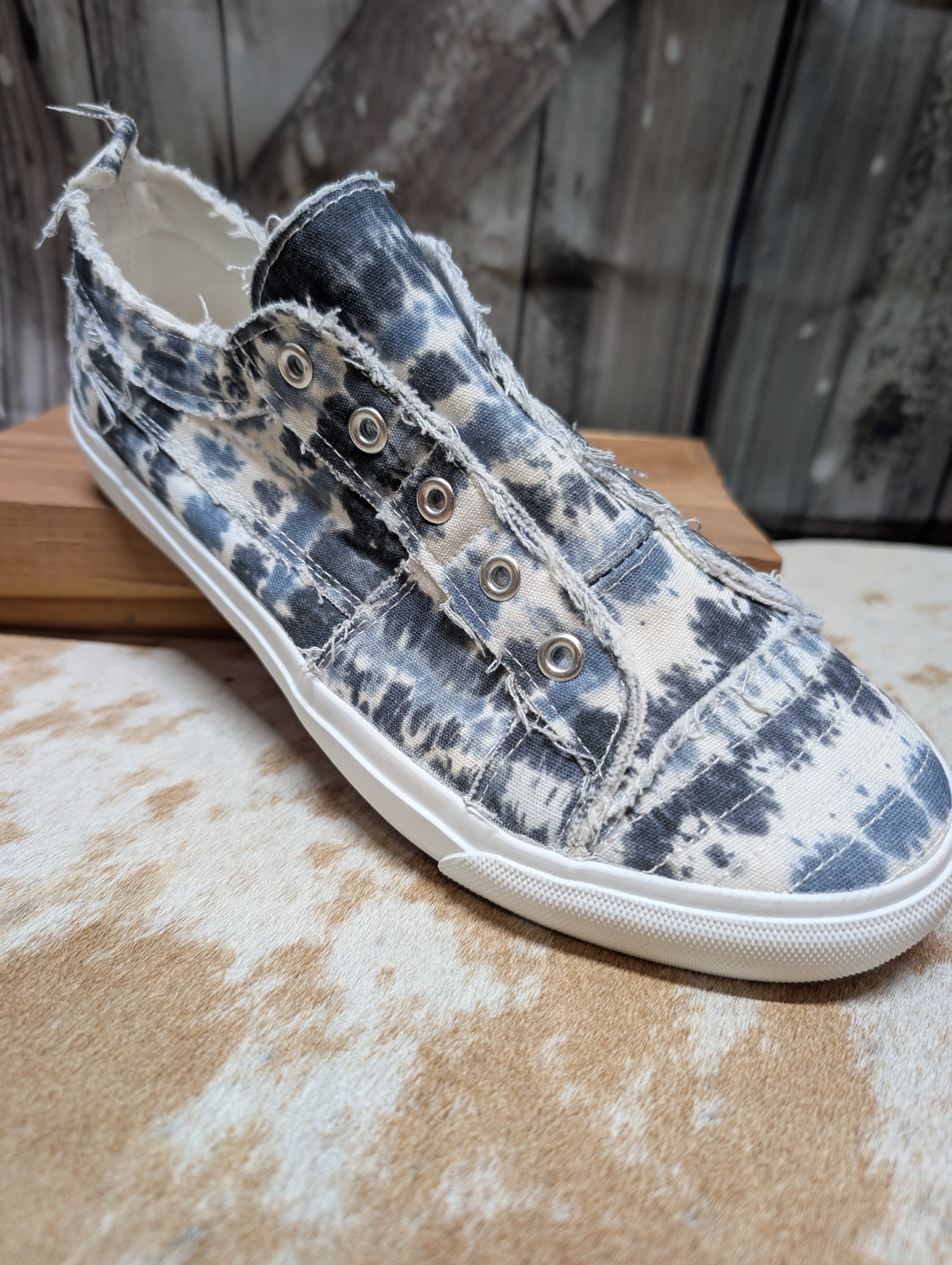 Blue and white tie-dye sneaker on a wooden surface with a rustic background