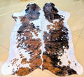 Cowhide rug with brown, black, and white pattern on a beige floor.