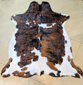 Brindle and white cowhide rug on a tan tile floor.
