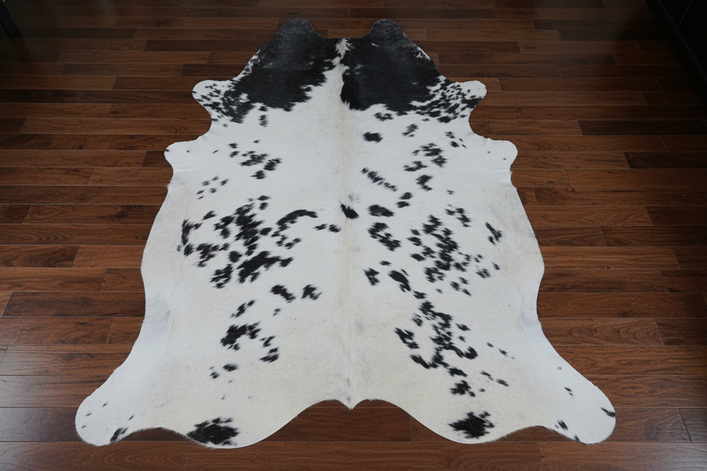 Black and white cowhide rug on a wood floor.