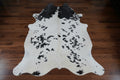 Black and white cowhide rug on a wood floor.