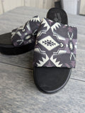 Pair of sandals with geometric pattern on a wooden floor