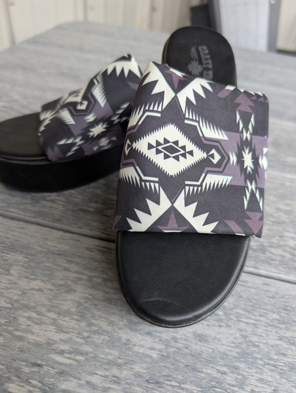 Pair of sandals with geometric pattern on a wooden floor