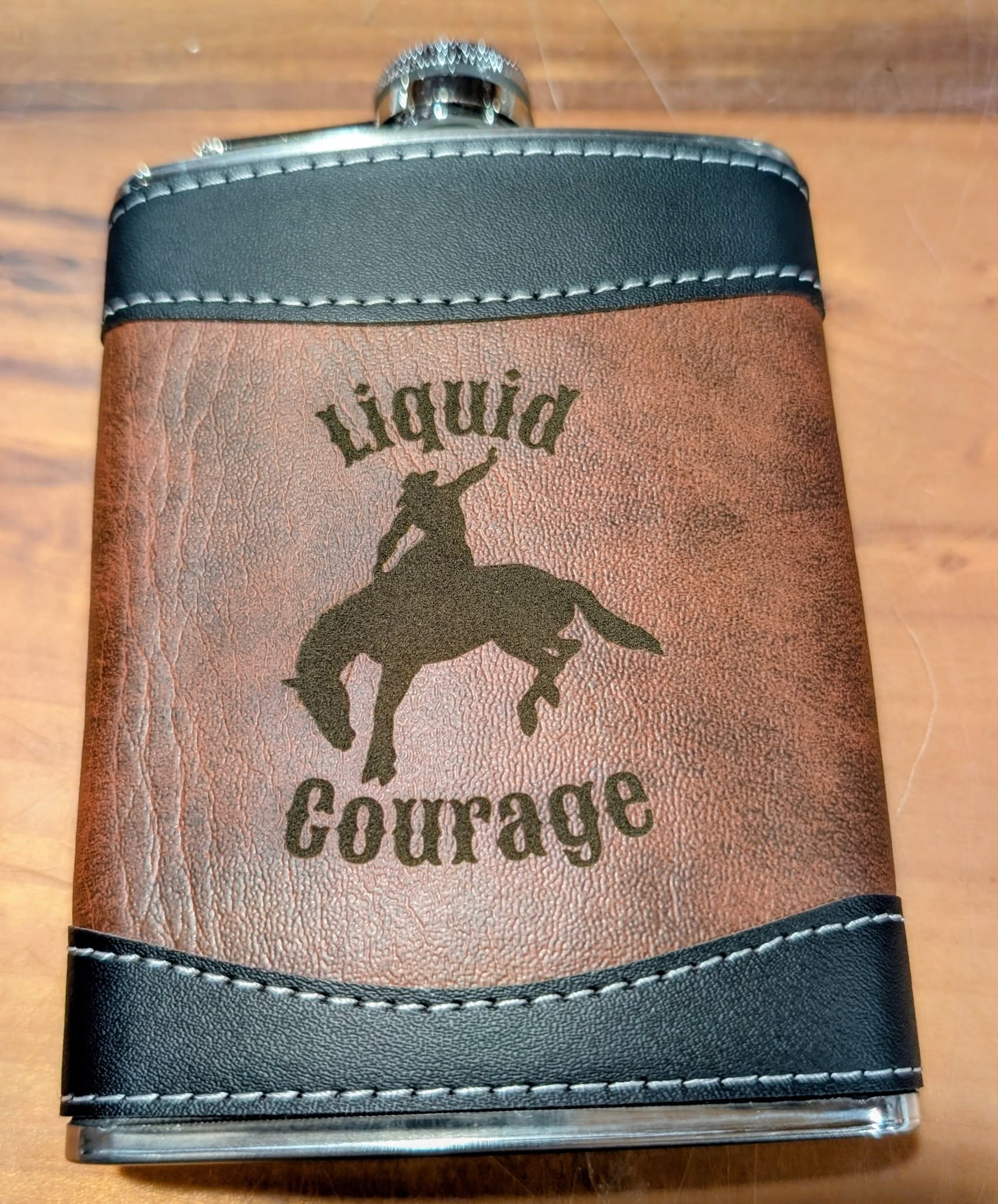 Flask with 'Liquid Courage' text and horse silhouette on a wooden surface