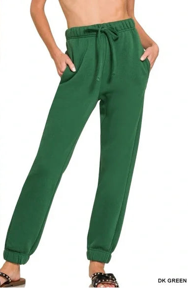 Green sweatpants worn by a person on a white background
