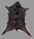 Dark brown goat hide rug with tan trim with a  gray background.