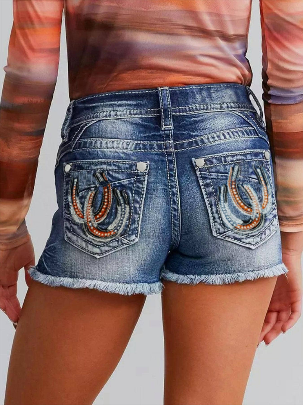 Person wearing blue denim shorts with horse shoe designs size large
