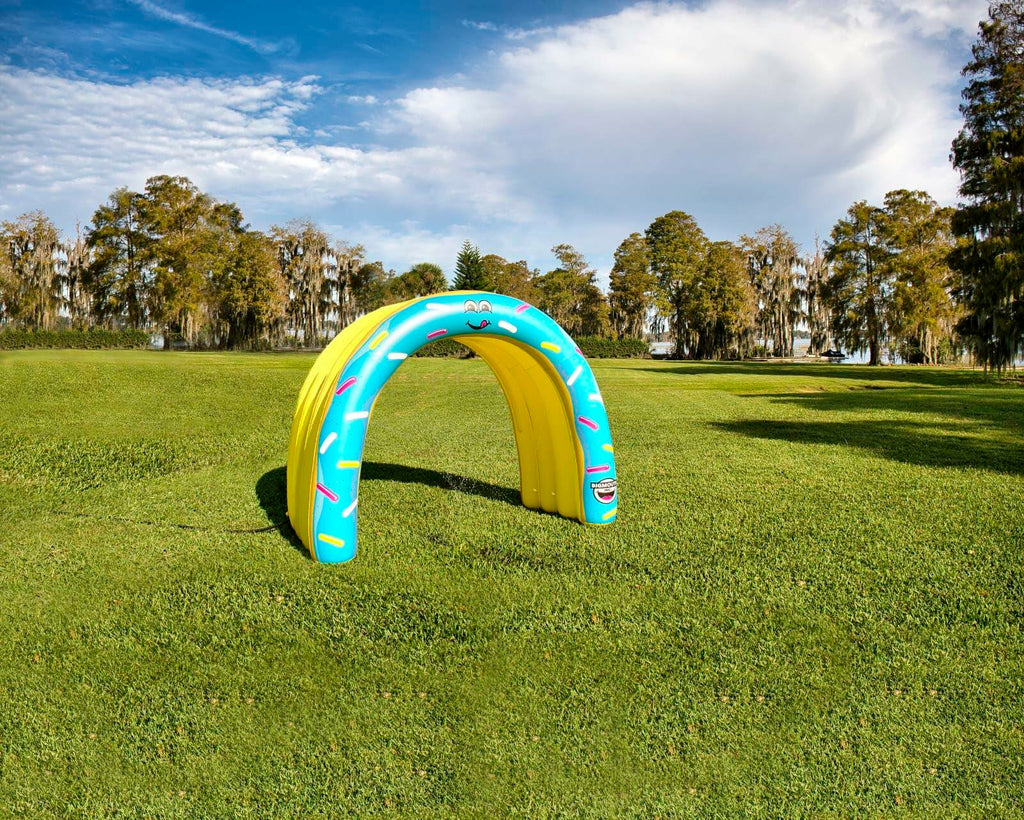 Colorful inflatable arch on a grassy field with trees in the background