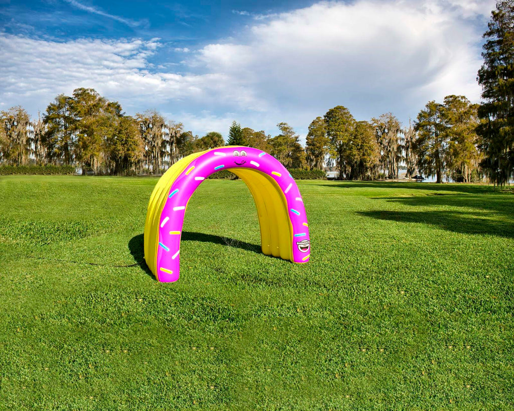 Inflatable archway with pink and yellow design on a grassy field