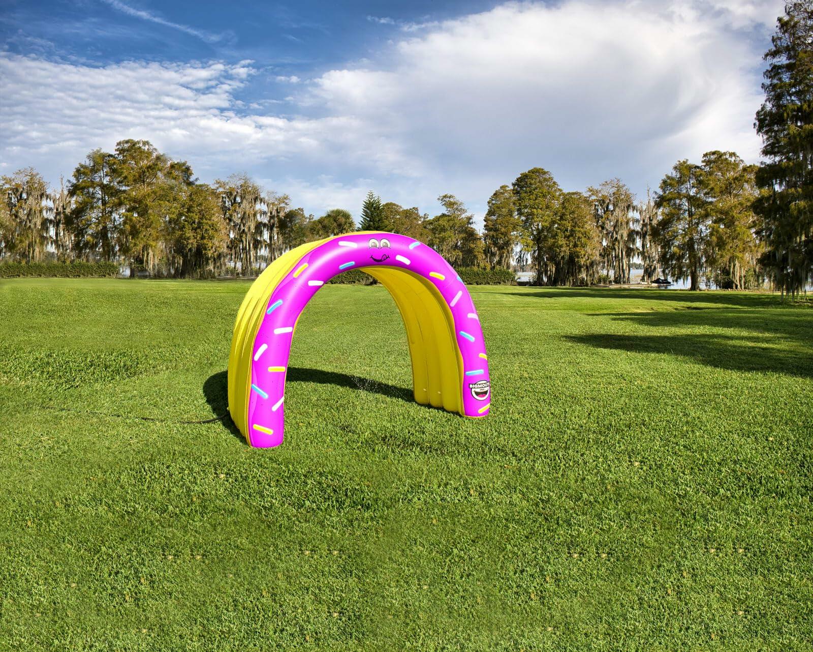 Inflatable archway with pink and yellow design on a grassy field