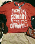 Everyone Wants to Be a Cowboy Graphic T-Shirt with necklace and wallet on a black and white backround