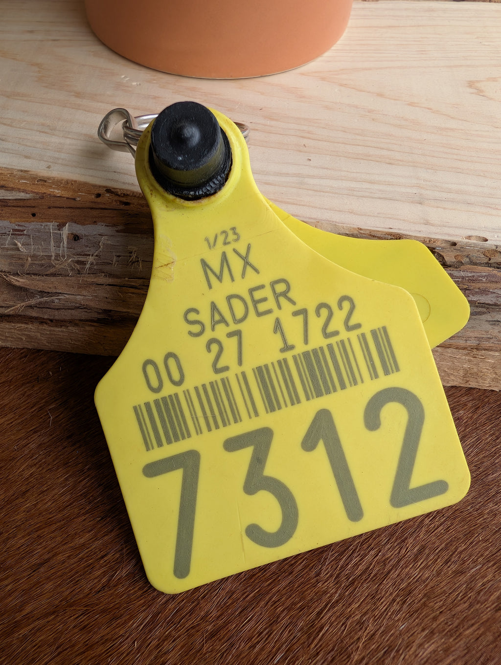 Cowtag keyring accessory laid flat on wood for rustic style
