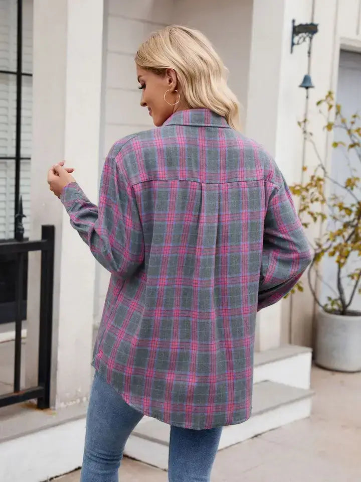 Person wearing a purple plaid shirt and jeans standing on a porch.