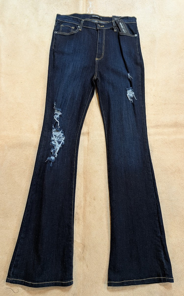 Pair of dark blue jeans with slight distressing on a beige surface
