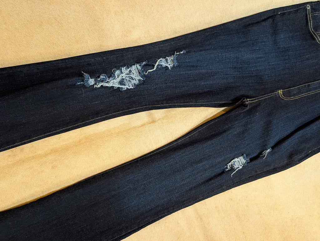 Distressed dark blue jeans on a beige background