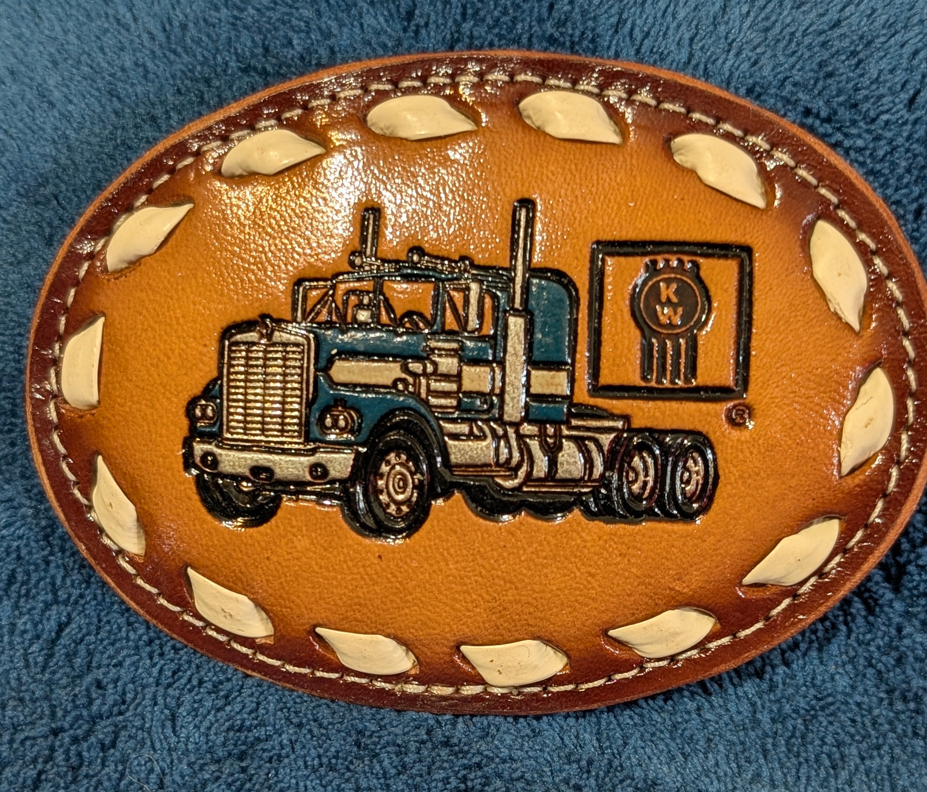 Leather belt buckle with truck design on a blue textured background