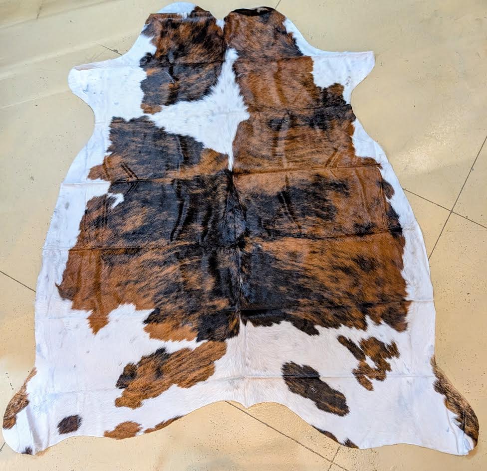 Cowhide rug with brown and black patches on a beige floor.