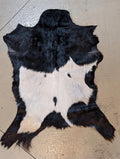Small black and white goat hide on a tile floor.