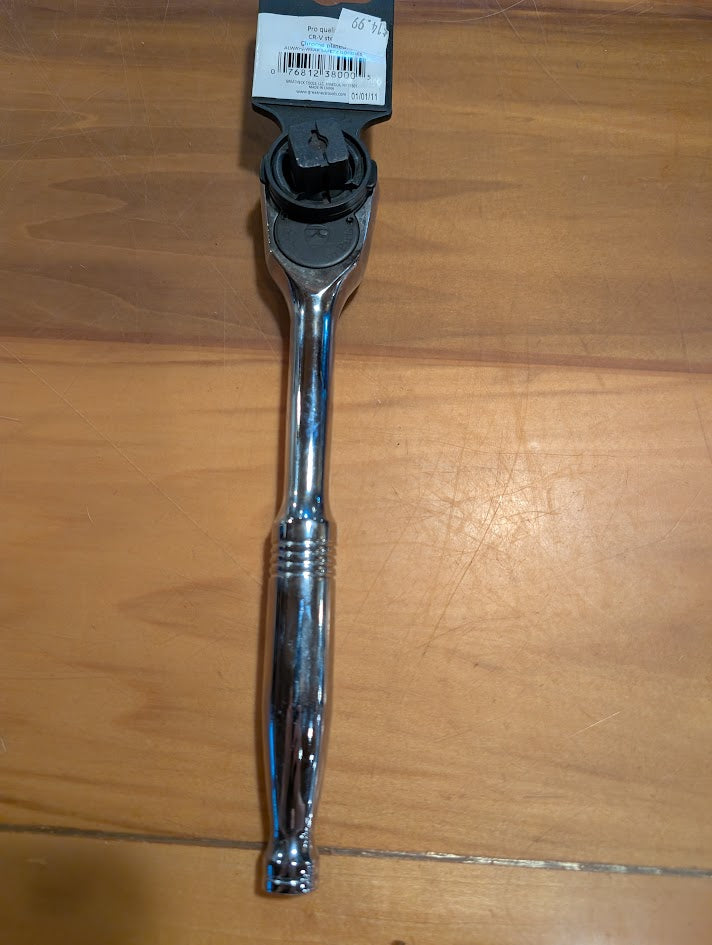 Chrome tear drop ratchet on a wooden surface with a label attached.