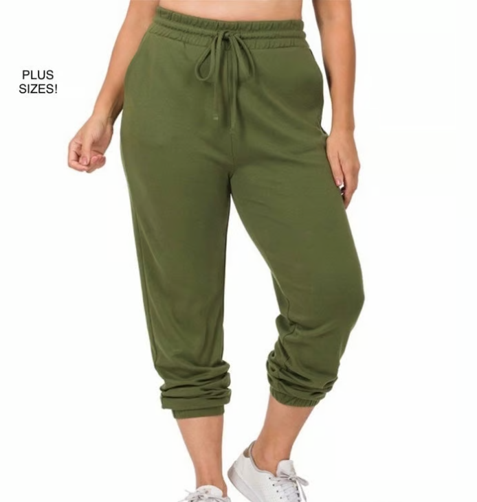 Green jogger pants worn by a person on a white background
