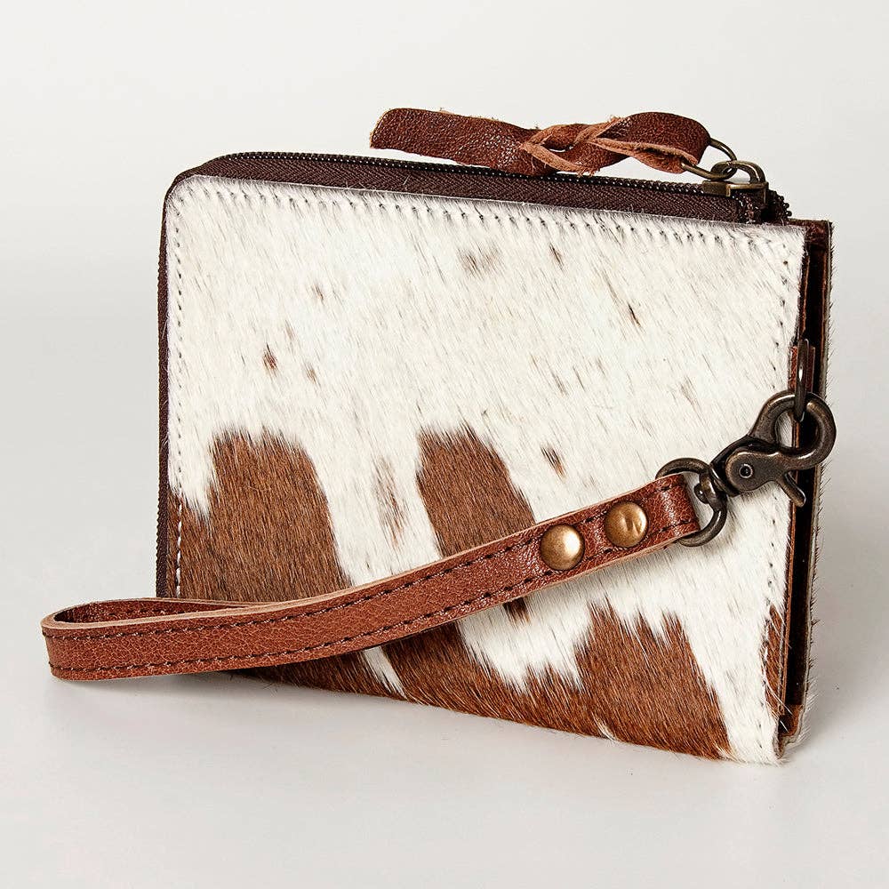 Small wallet/coin pouch with cowhide pattern and brown leather strap on a light gray background
