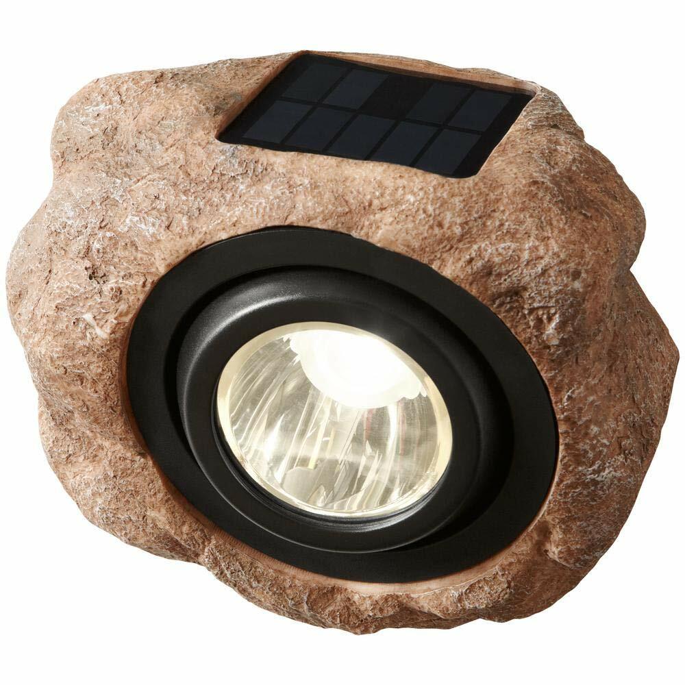 Solar-powered outdoor light designed like a rock with a visible solar panel on a white background.