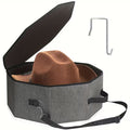 Gray hat box with a brown felt hat inside, black lid, and carrying strap on a white background.