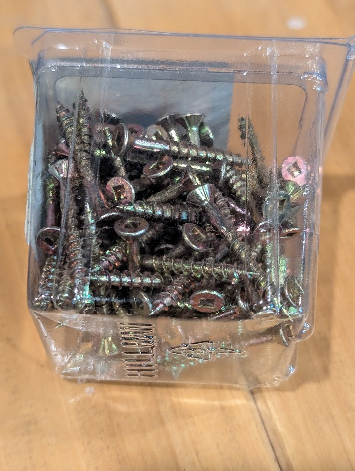 Clear plastic container filled with screws on a wooden surface