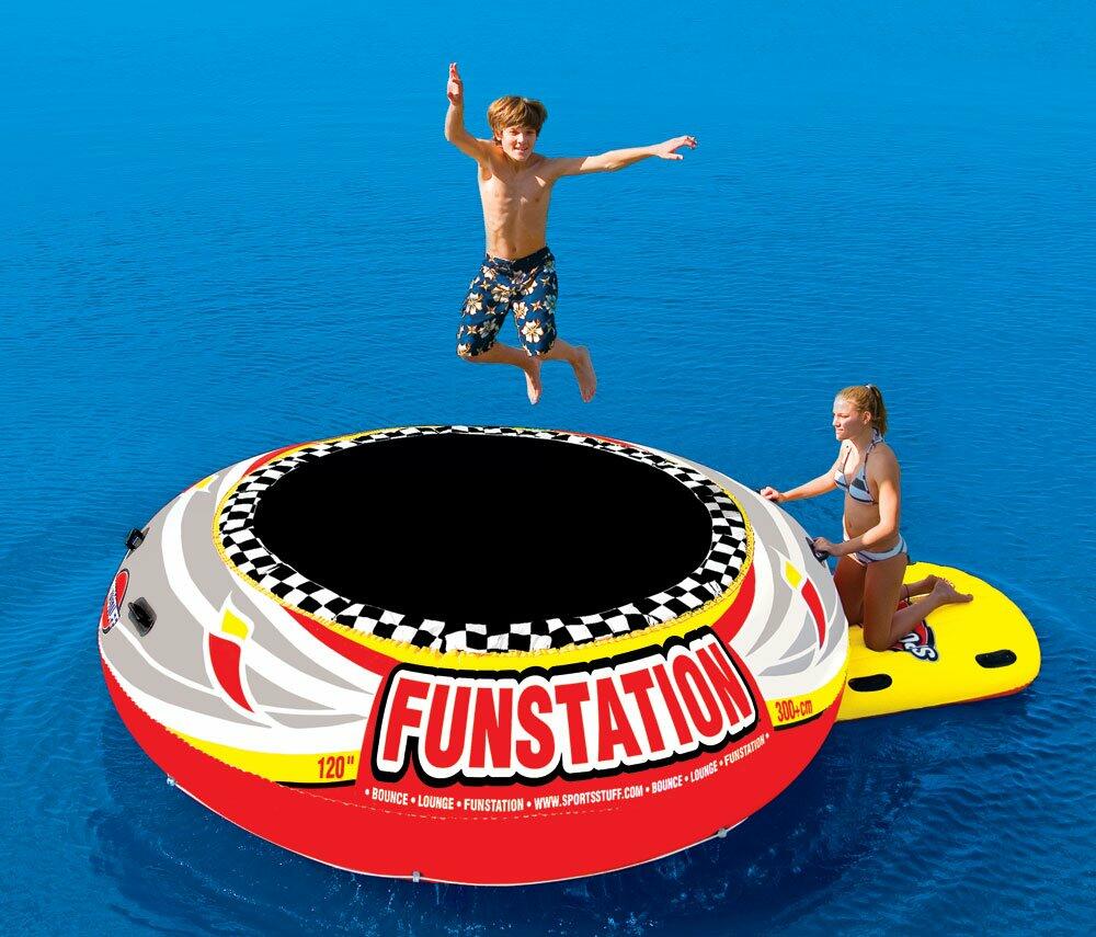 Children playing on a Funstation inflatable trampoline in the water.