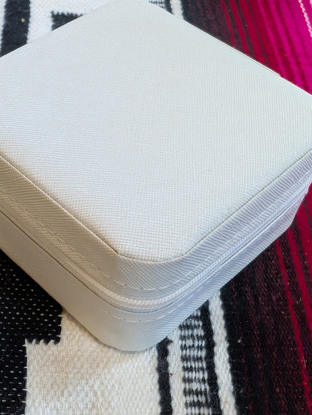 Closed ivory jewelry case next to travel accessories