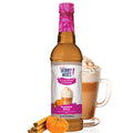 A bottle of Jordan's Sugar Free Pumpkin Spice Syrup with a glass of coffee and whipped cream on the side, set against a white background.