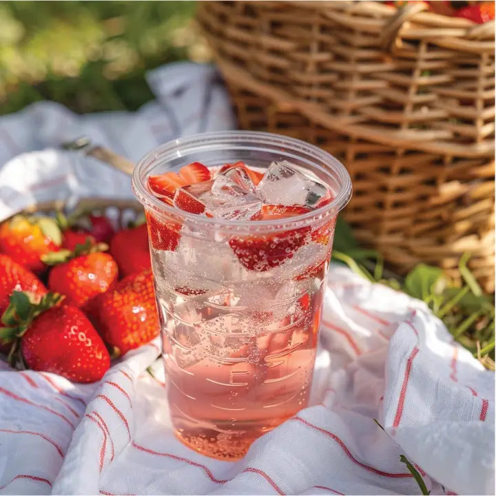 A glass of pink strawberry lemonade with Jordan’s Skinny Mix syrup beside it.