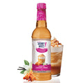 A bottle of Jordan's Skinny Syrups Sugar Free Coffee Syrup in Vanilla Caramel Creme flavor, displayed with a prepared beverage and ingredients around it.