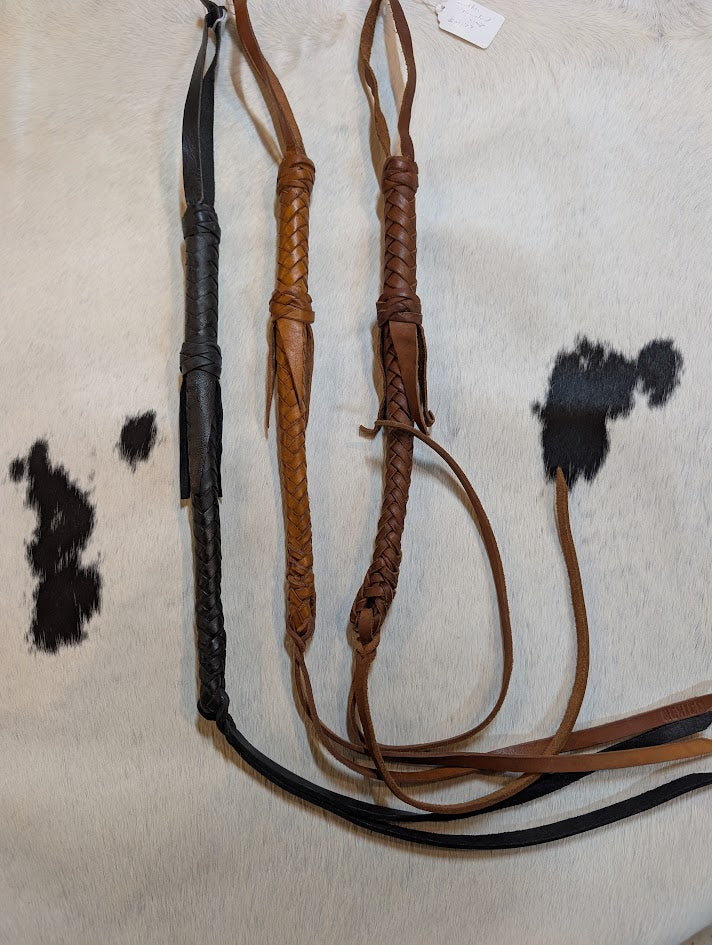 3 leather braided whips on a cowhide rug