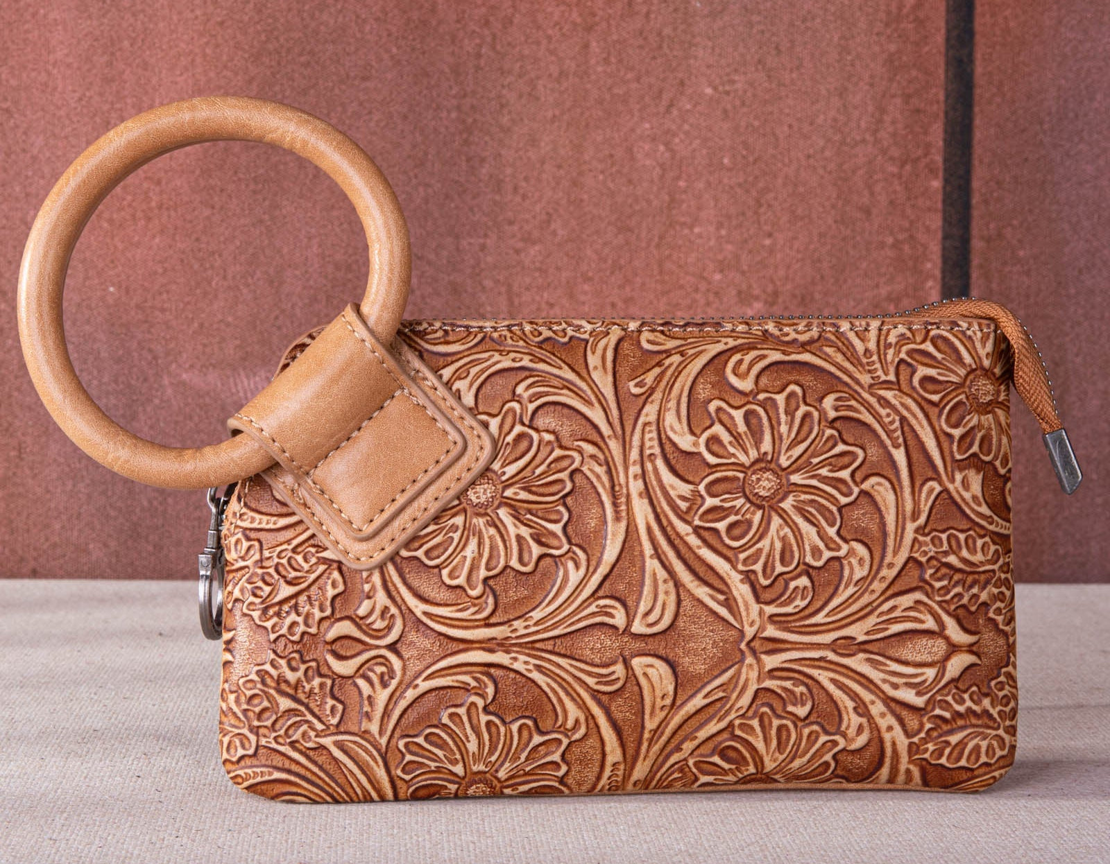 "Western-style PU leather clutch bag with floral tooling and top zipper"