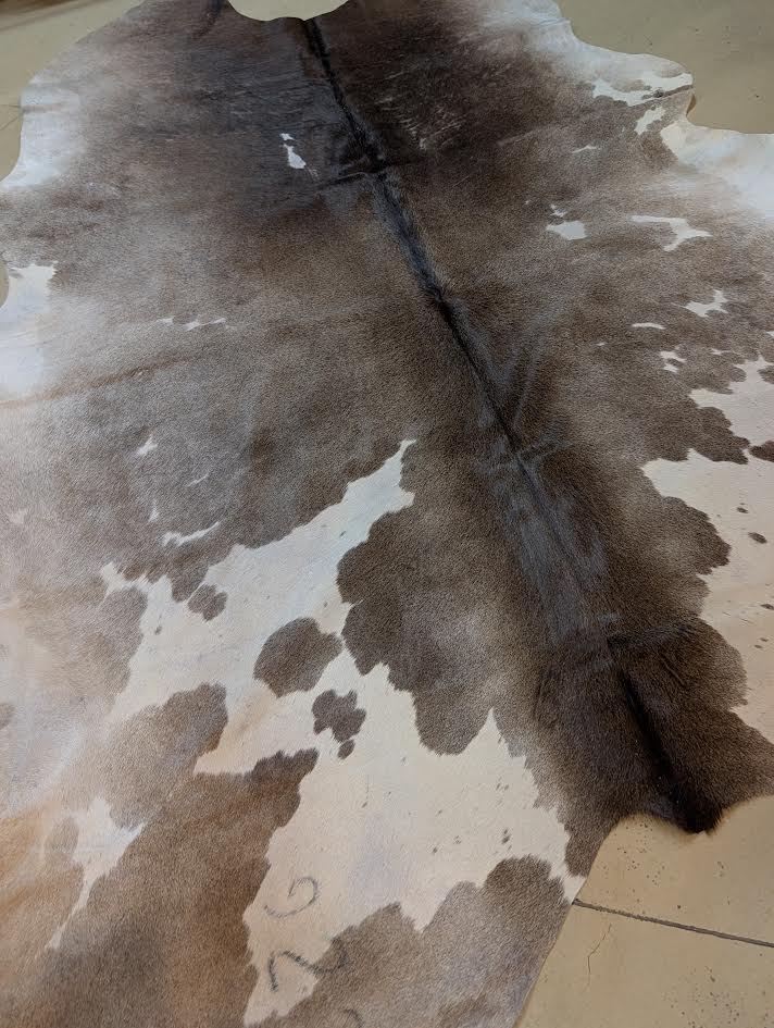 Brown and white cowhide rug on a tiled floor