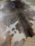Brown and white cowhide rug on a tiled floor