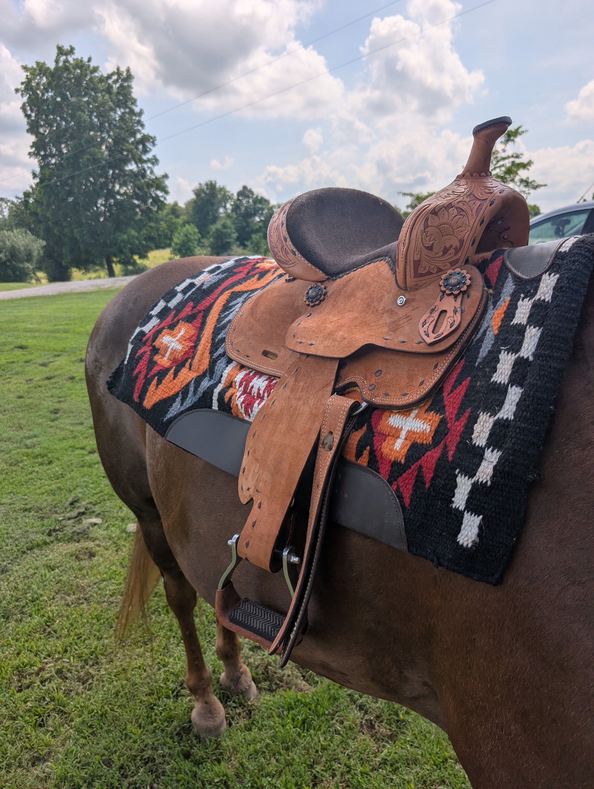 Lightweight youth barrel saddle with hand tooling, in-skirt rigging, and aluminum stirrups.
