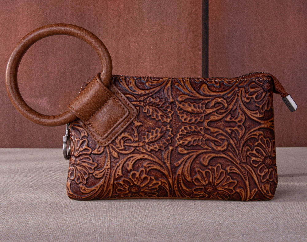 "Montana West floral tooled wristlet clutch with silver ring handle on rustic wood background"