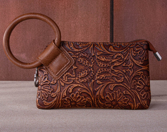 "Montana West floral tooled wristlet clutch with silver ring handle on rustic wood background"