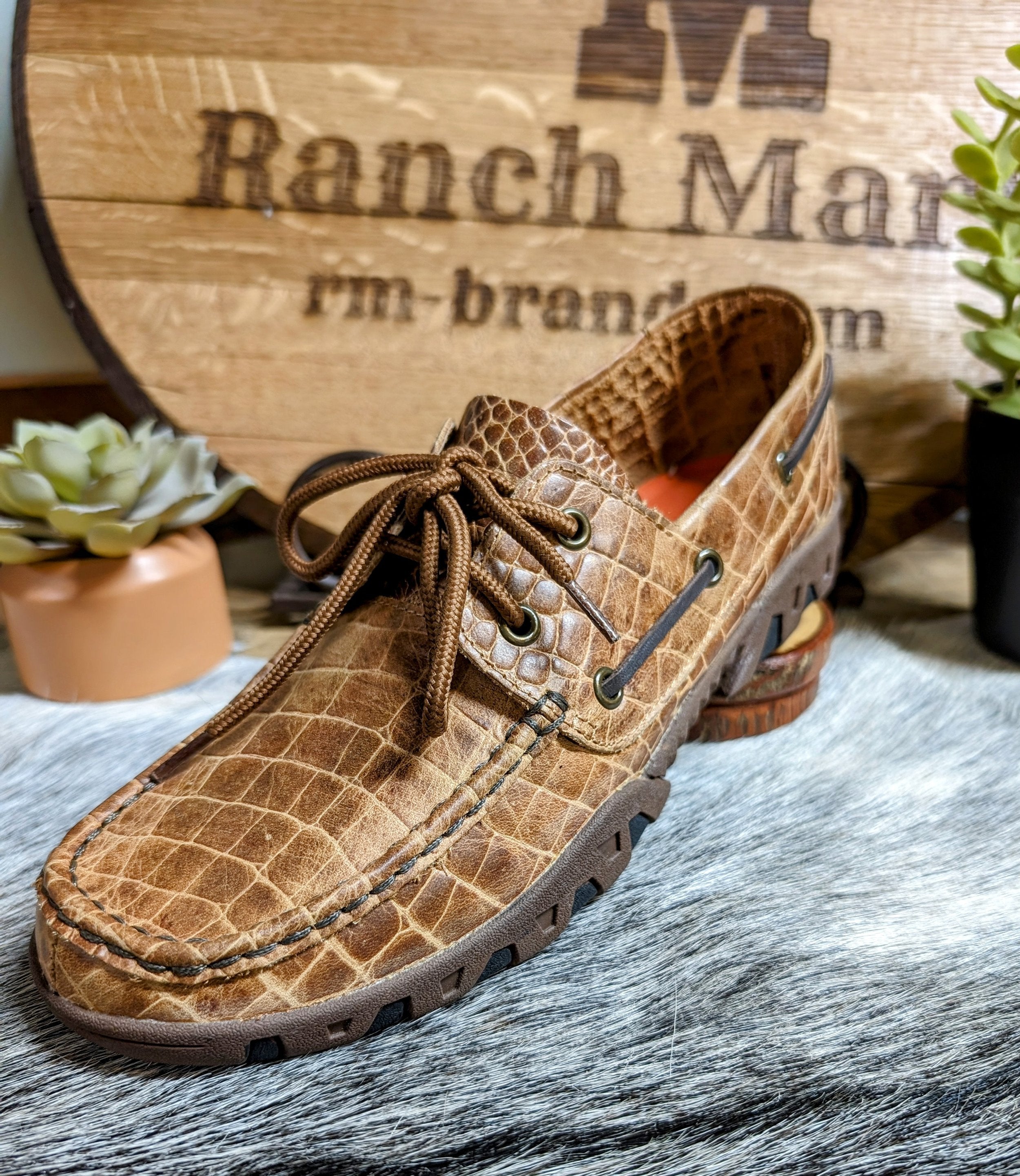 A brown Ferrini men's loafer with an alligator belly cowhide print displayed on a ranch-style background.