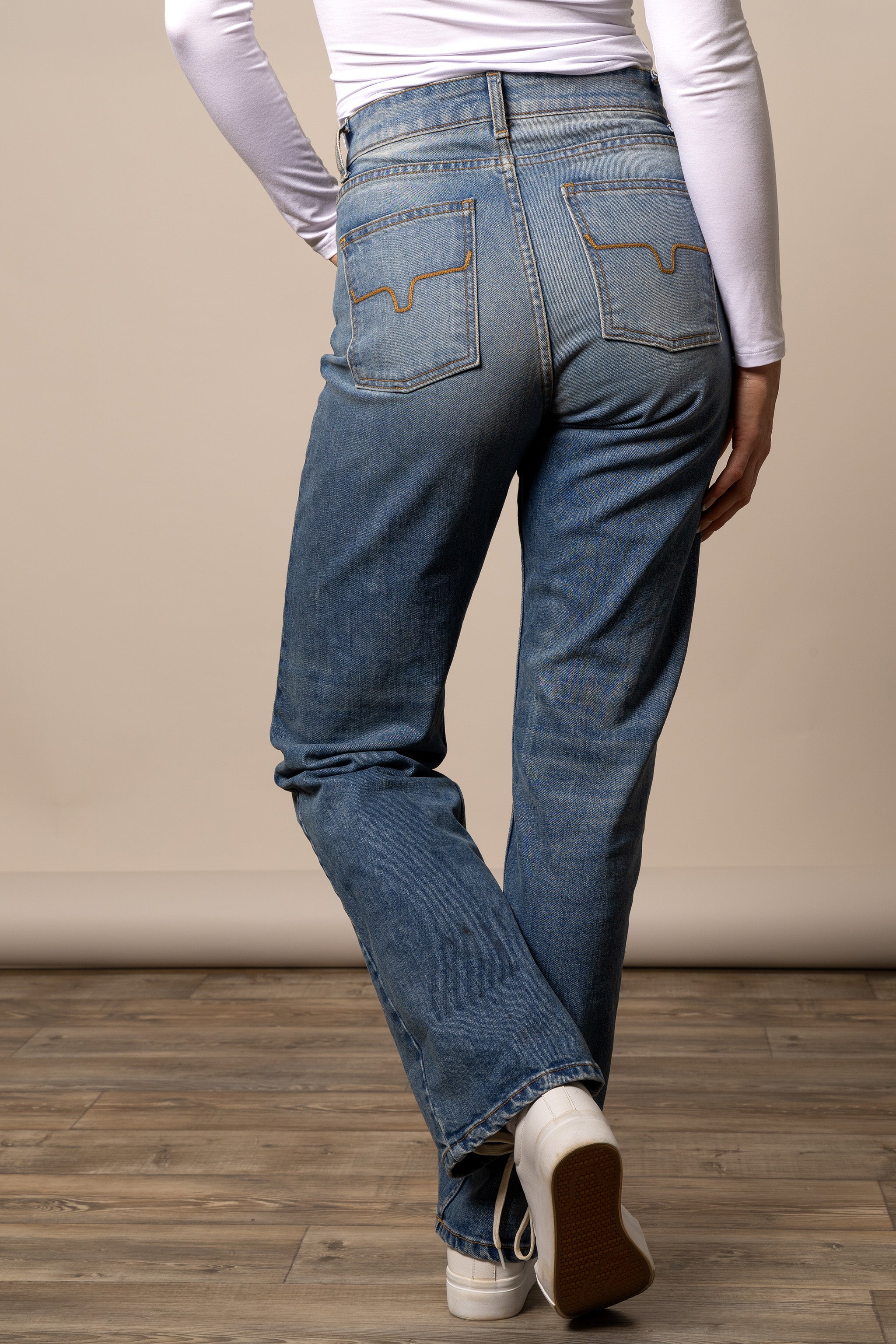Back view of Kimes Ranch Mia women's relaxed boyfriend jeans paired with a white long-sleeve shirt.