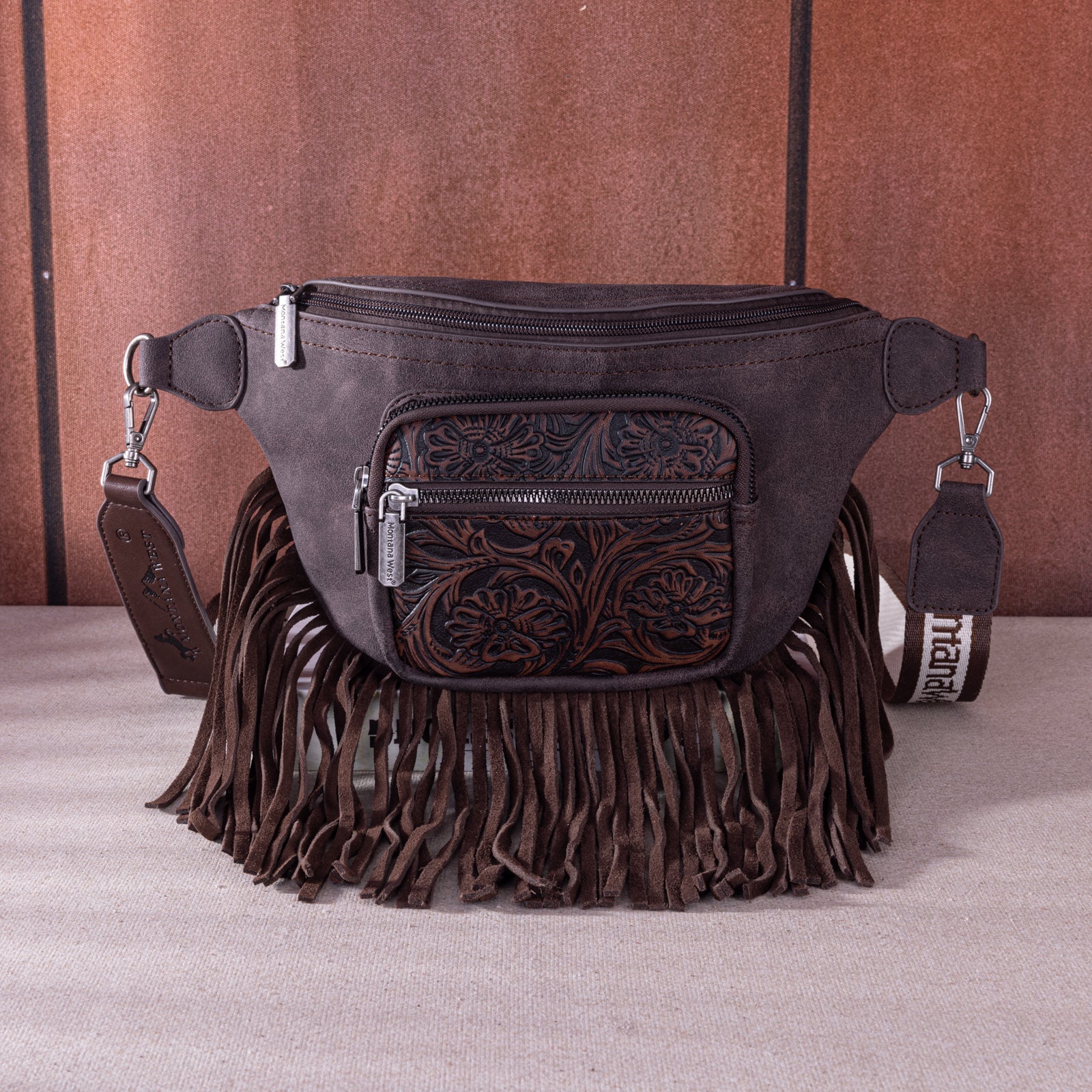 Western suede fringe waist bag by Montana West, featuring floral tooled leather design and zippered compartments.
