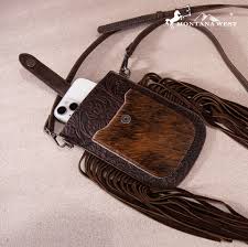 Phone case with cowhide design and fringes on a beige background