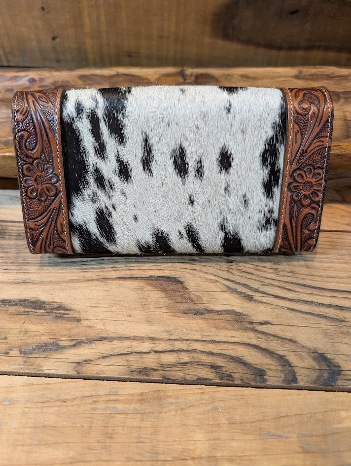 Wallet with cowhide pattern and brown leather trim on a wooden surface