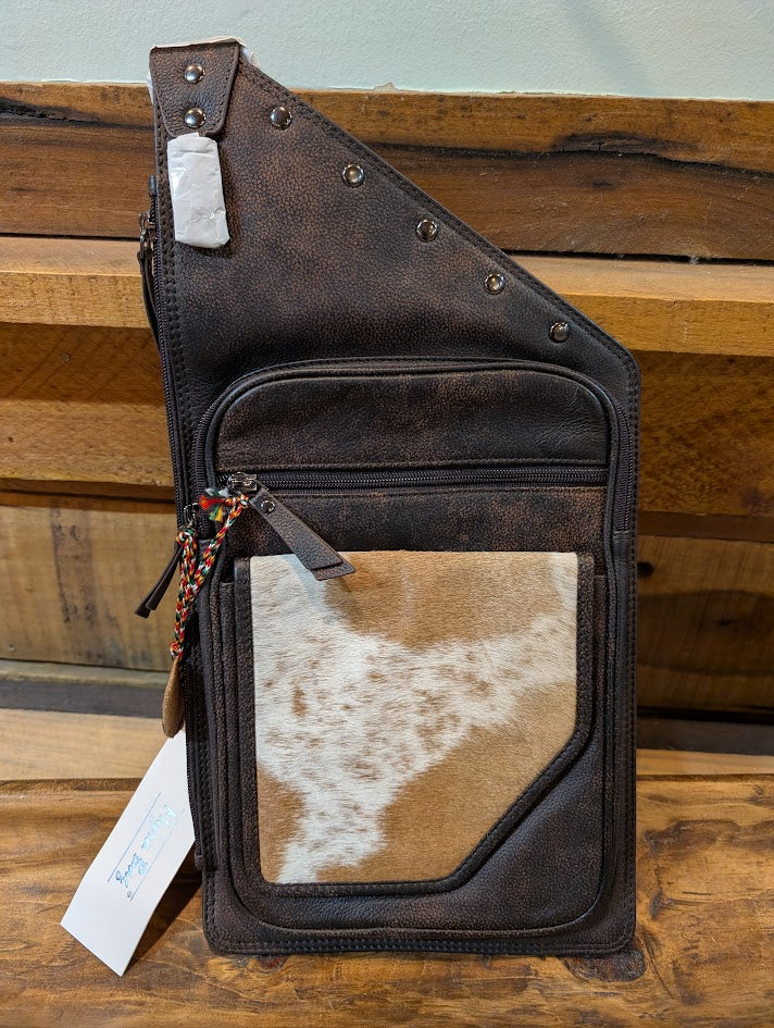 Brown leather bag with cowhide pattern on a wooden surface